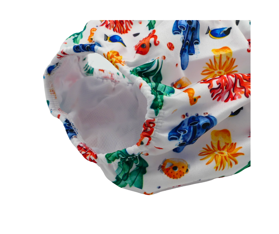 Eine Nahaufnahme der Lumina Schwimmwindel, einer weißen, atmungsaktiven PUL-Schwimmwindel mit farbenfrohen aquatischen Prints - Fische, Algen, Korallen -, elastischen Rändern und einem weichen Futter, ideal für Babyschwimmen.