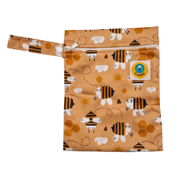 Die Lumina Mini Wetbag mit Schlaufe & YKK Zipper ist aus recyceltem PUL gefertigt, hat ein fröhliches Bienen- und Wabenmuster auf Gelb und einen grünen Globusaufnäher - ideal für Damenhygieneprodukte.