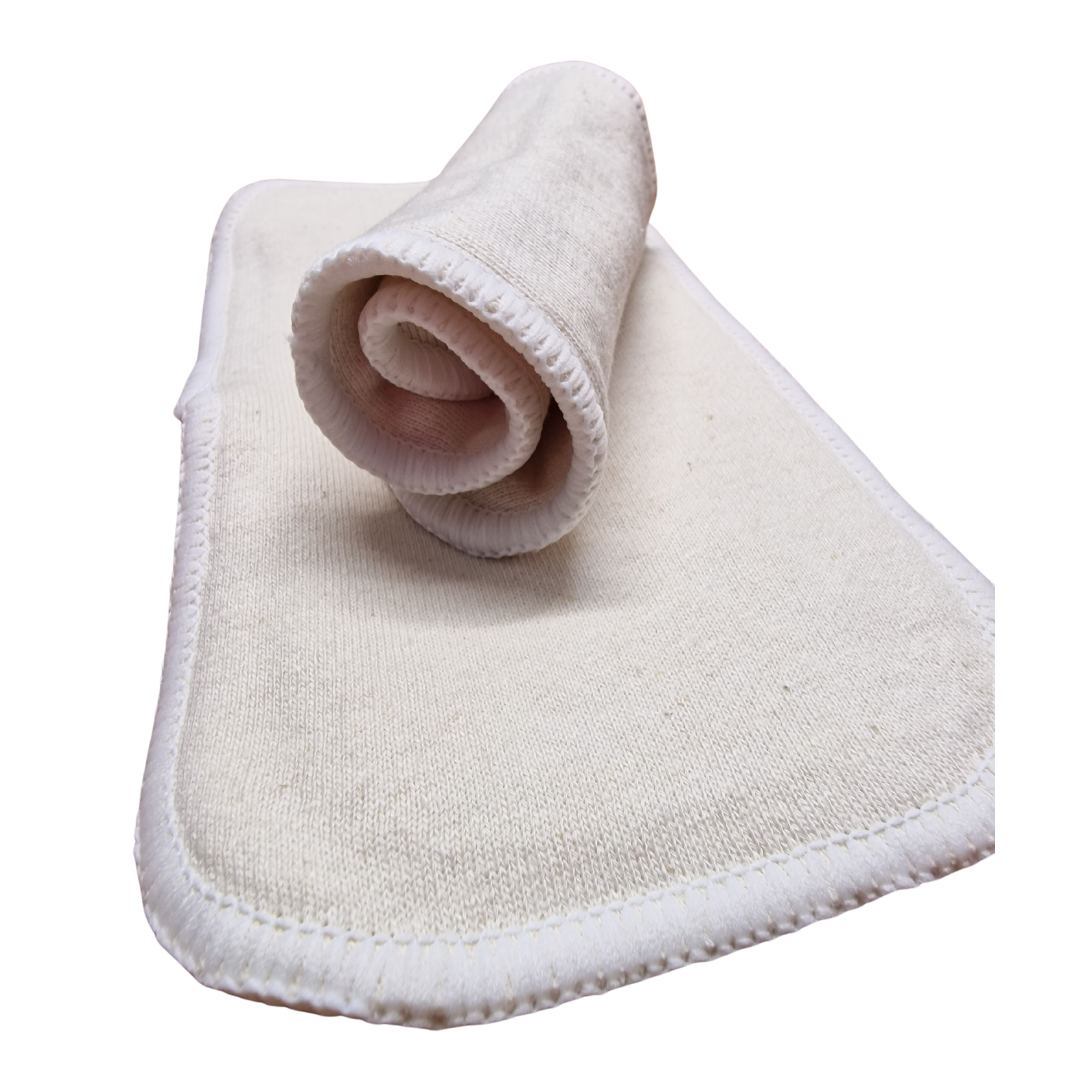 Auf einer flachen, rechteckigen Lumina-Einlage mit abgesteppten Rändern sitzt eine gerollte Lumina Hanf Booster Mini-Stoffauflage; beide sind aus weichem, cremefarbenem Hanf/Baumwolle-Stoff gefertigt.