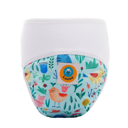 Der Pull-me-Up All in One Windel One-Size von Lumina hat ein weißes Oberteil und eine bunte Vorderseite mit Vögeln, Blumen und Blättern. Er ist aus GOTS-zertifizierter BioBaumwolle gefertigt und hat einen runden Lumina-Aufnäher mit blauem Baum-Logo.