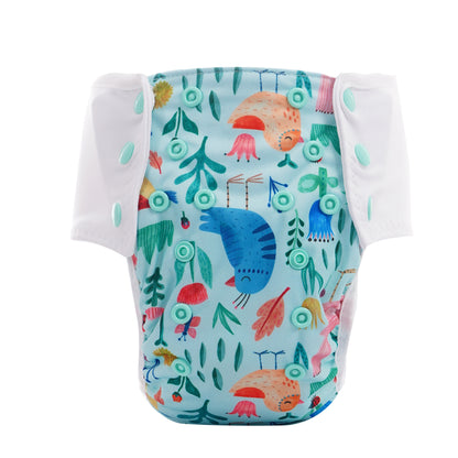 Der Lumina Pull-me-Up All in One Windel One-Size hat weiße Seitenlaschen und einen farbenfrohen Naturdruck mit Vögeln, Blättern und Pflanzen auf hellblauem Grund, gefertigt aus GOTS-zertifizierter Bio-Baumwolle.