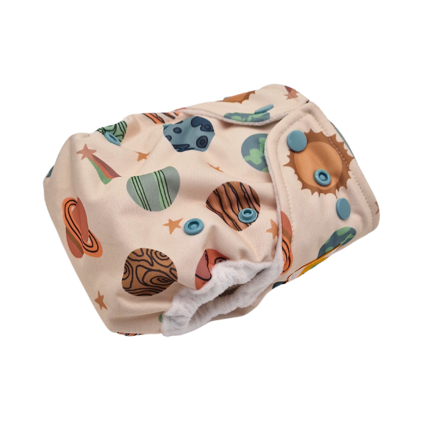 Die Lumina Überhose für Neugeborene ist eine wiederverwendbare Stoffwindel mit blauen Druckknöpfen, die ein farbenfrohes Weltraummotiv mit Planeten, Sternen und der Sonne auf weichem, hellbeigem Minky-Vlies zeigt.